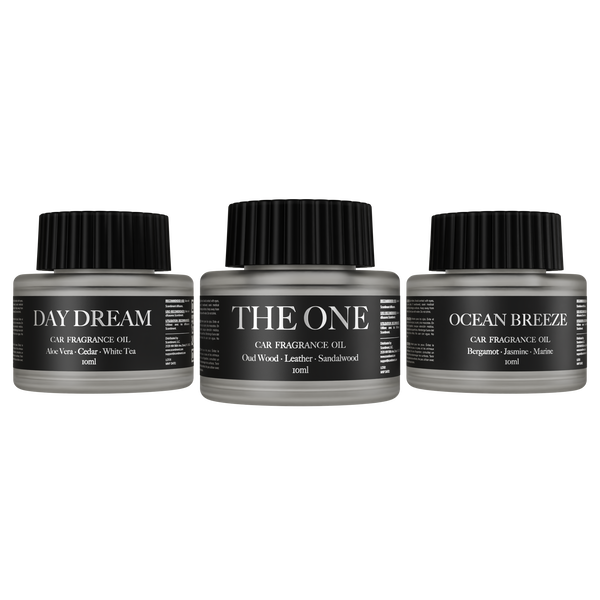 Three car fragrance oil bottles labeled 'Day Dream', 'The One', and 'Ocean Breeze' on a white background.