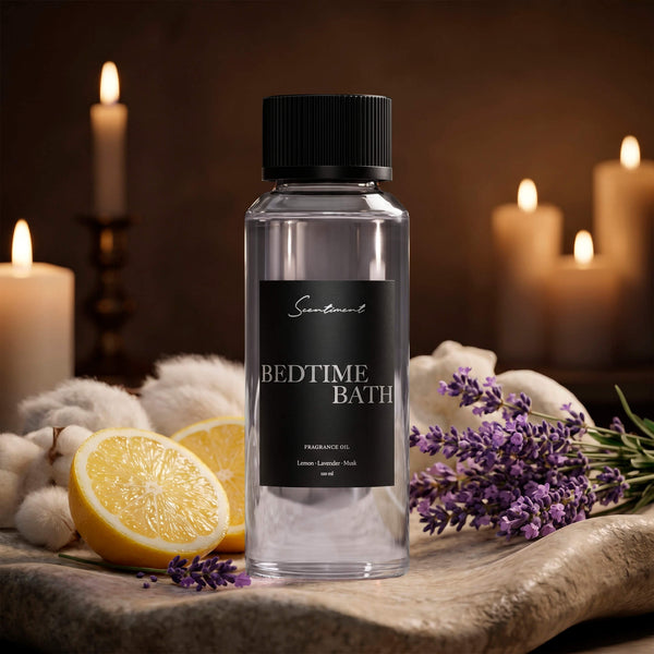 Scentiment Bedtime Bath diffuser fragrance oil bottle with slice of lemons and lavender on a stone surface surrounded with candles.