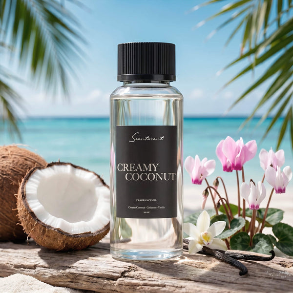 Scentiment Creamy Coconut diffuser fragrance oil with coconuts, vanilla beans and pink tulips on a wooden log overlooking the ocean.