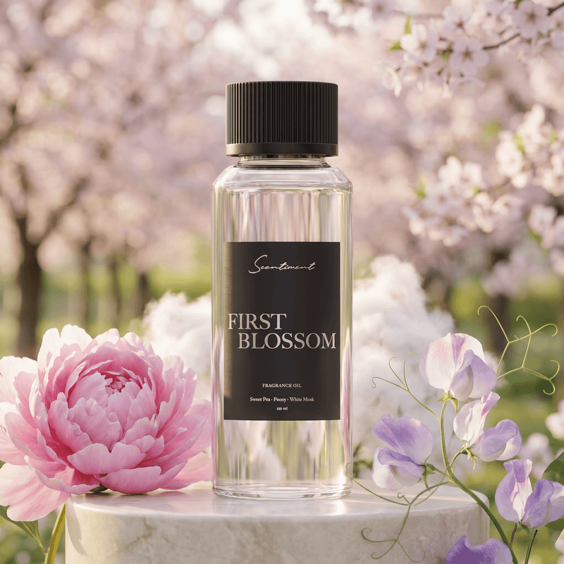 First Blossom diffuser fragrance oil bottle on a white marble stone with cherry blossoms in the background.